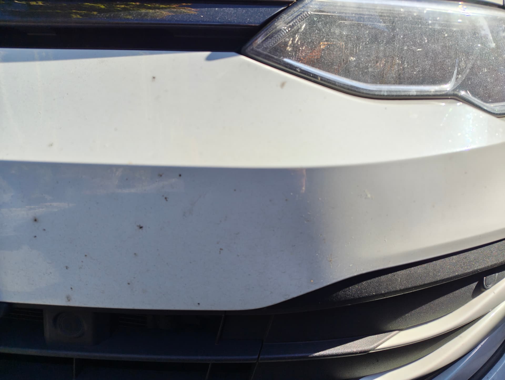 Golf front bumper and headlight covered in insect splatter and grit before wash